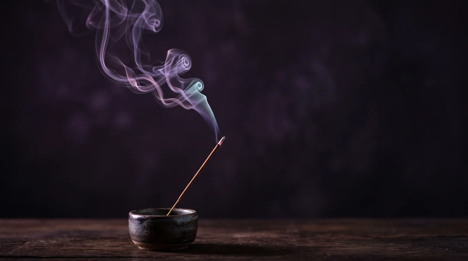 A single incense stick in a dark ceramic holder, a ribbon of smoke curling upward through lavender and aqua light against deep aubergine.