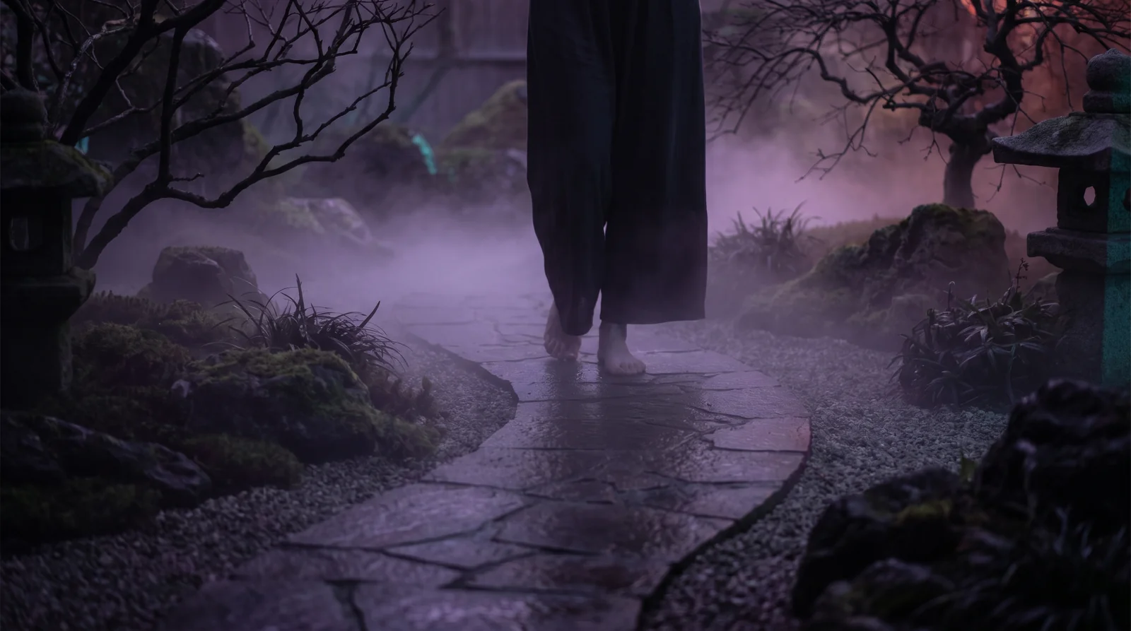 A misty stone path through a quiet garden at dusk, lit softly along its edges.
