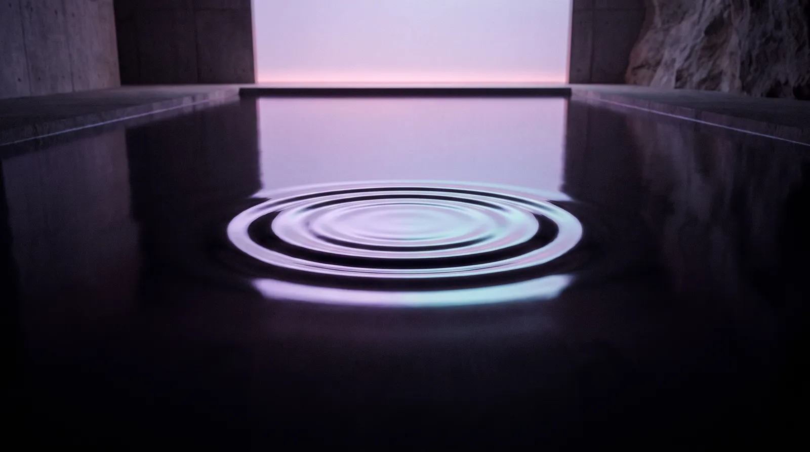 A single ripple spreading across still, dark water under deep aubergine light, fading into perfect calm.