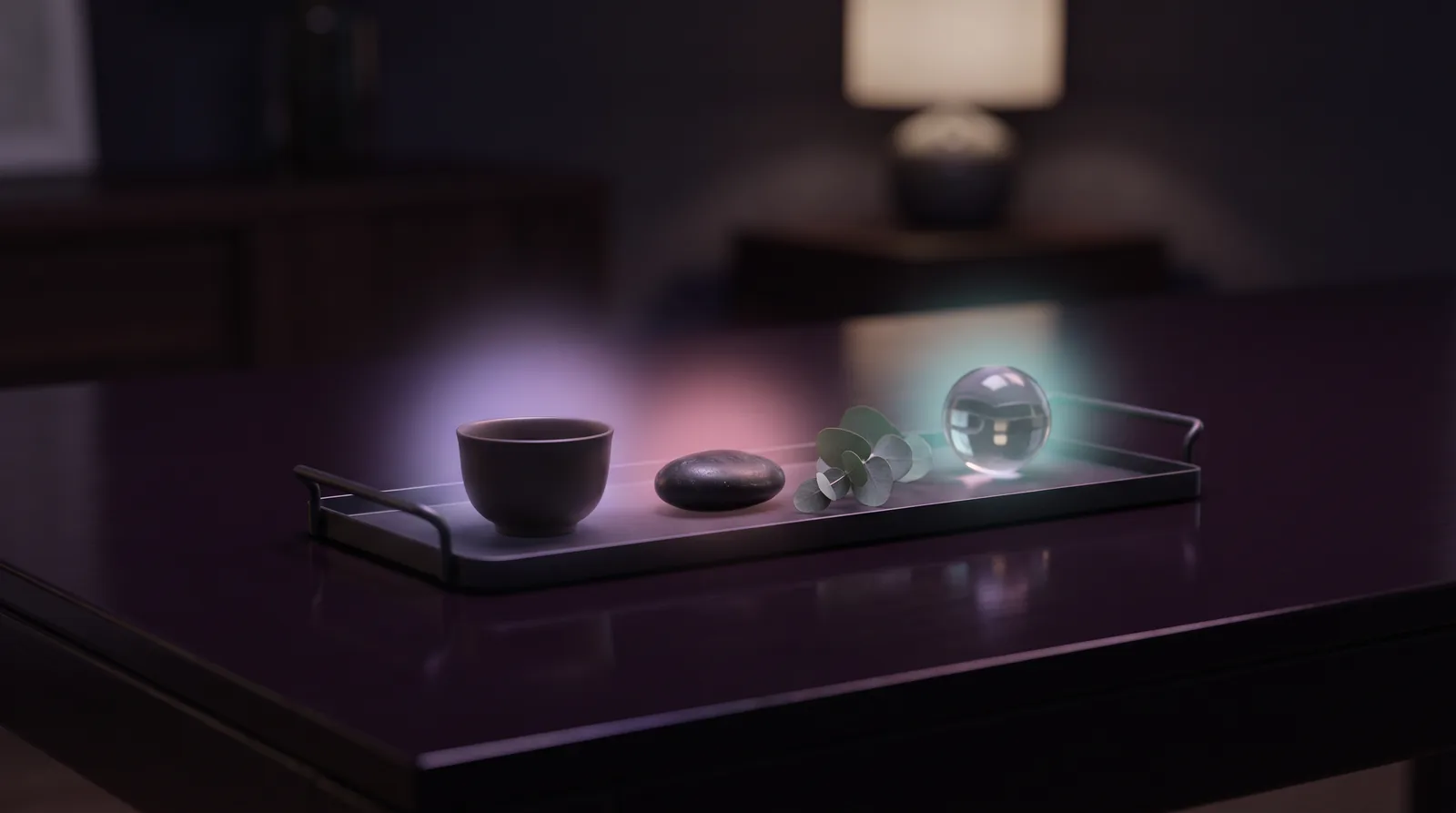A dark elegant tray arranged like a tasting menu with small glowing objects: a tiny teacup, a smooth stone, a leaf sprig and a glass orb haloed in lavender and aqua light.